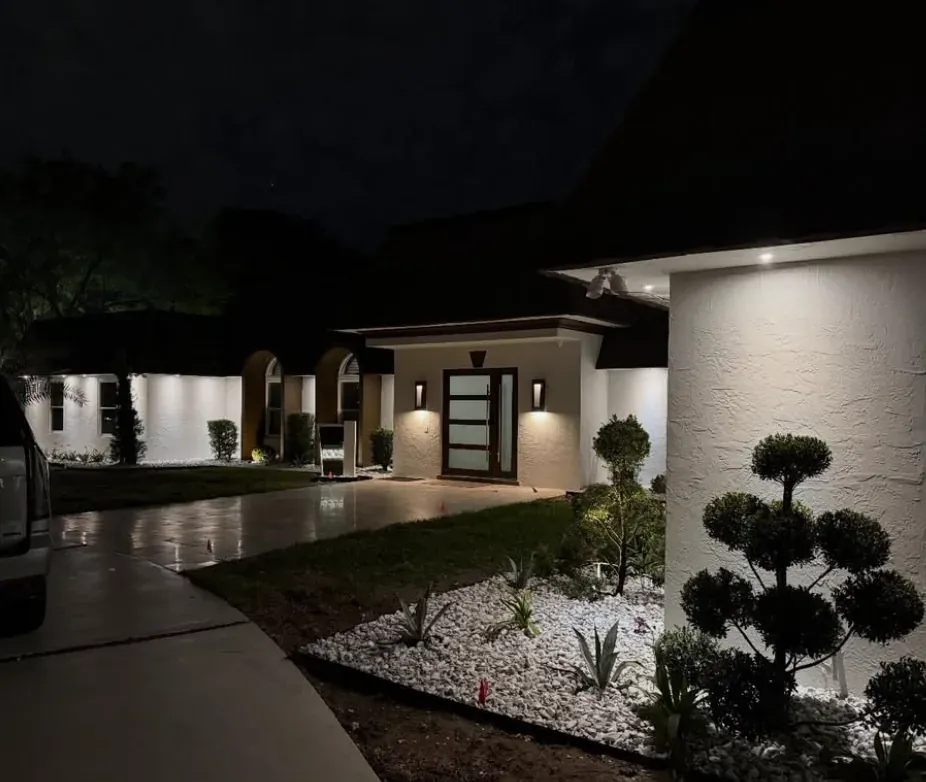 Modern home exterior at night with integrated landscape lighting